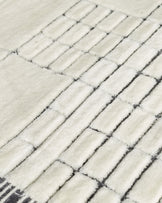 Close-up of medium sculpted wool rug in monochrome, showing textured herringbone weave pattern in cream and charcoal.