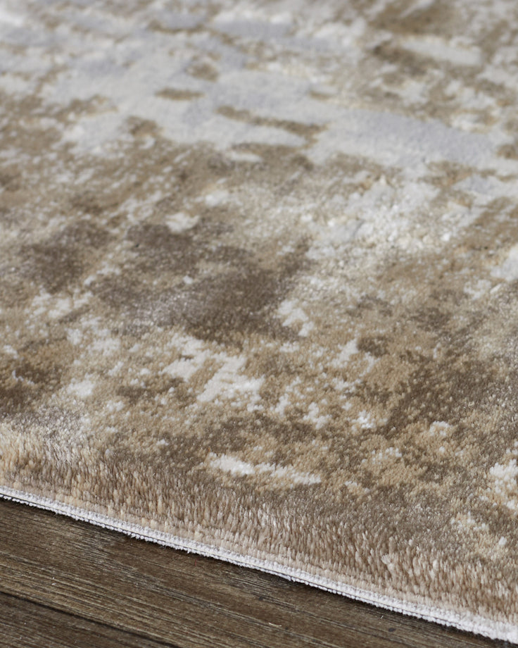 Distressed border medium textured rug in natural tones, showing cream and beige pattern detail on wooden floor.