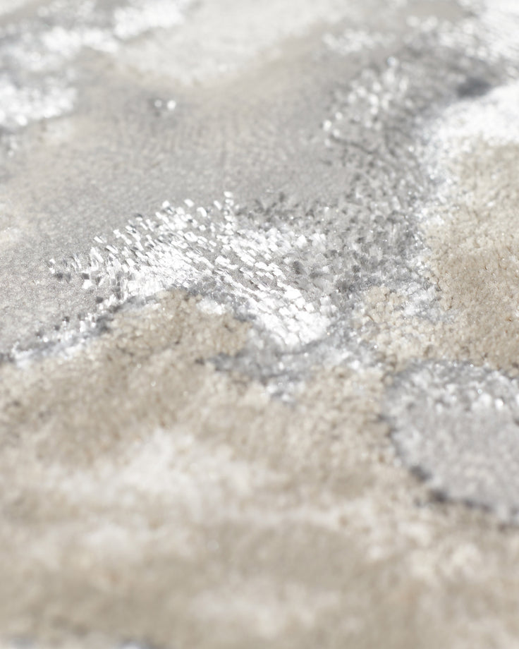 Close-up of Perla medium rug texture showing soft silver and cream tones with shimmering metallic finish detail.