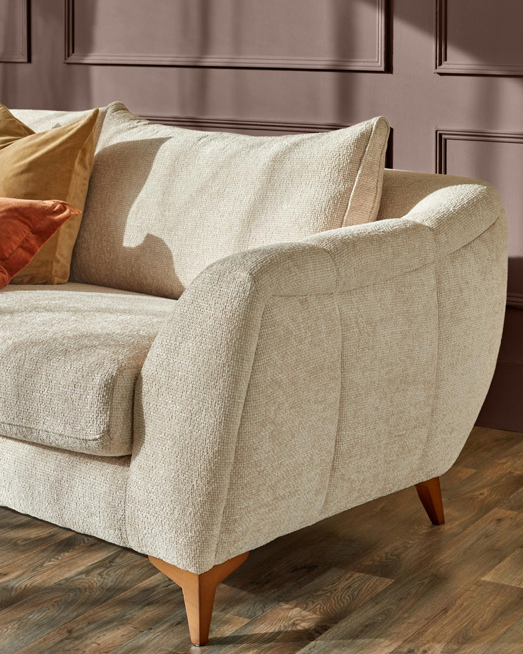 A modern cream sofa with wooden legs sits against a stylish brown wall with decorative panelling.
