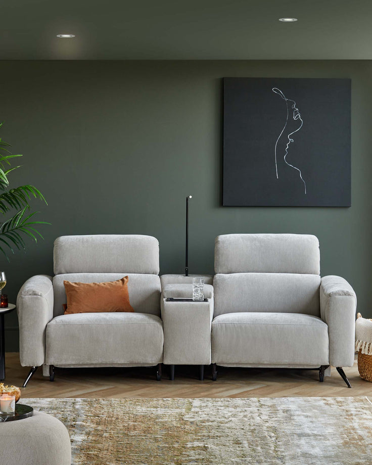 Two cozy, light gray armchairs with a shared side table featuring a glass inlay, accented by a decorative pillow and a soft rug.