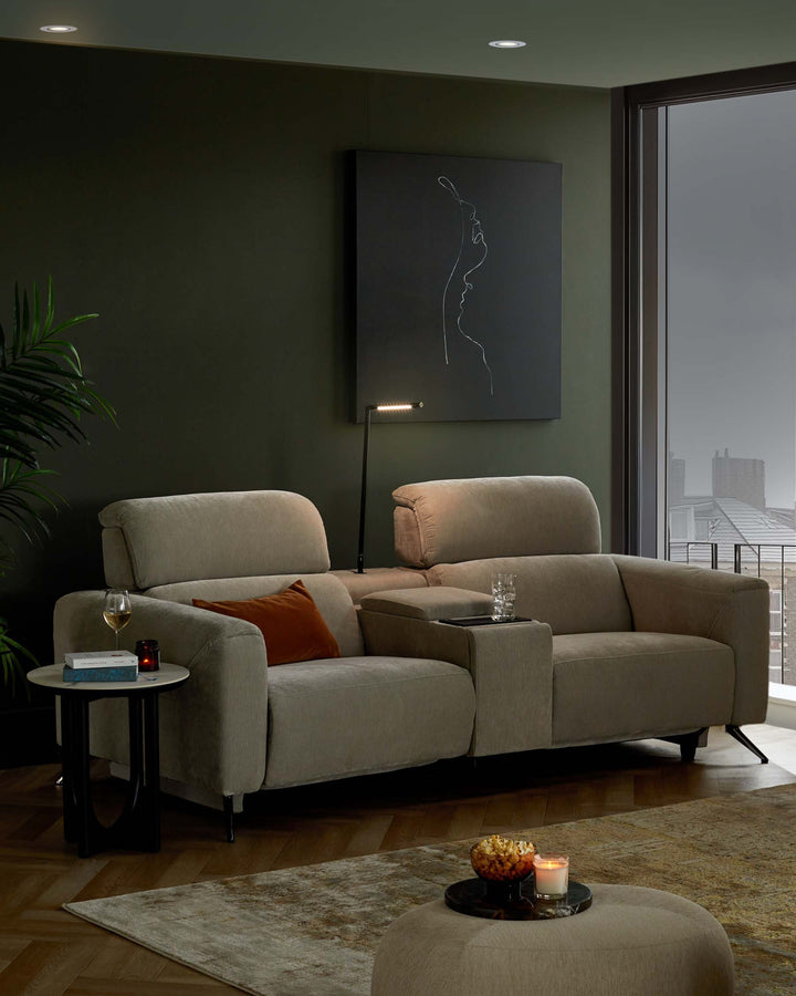 A contemporary sectional sofa with plush cushions, a side table, and a round ottoman, complemented by a modern lamp and wall art.