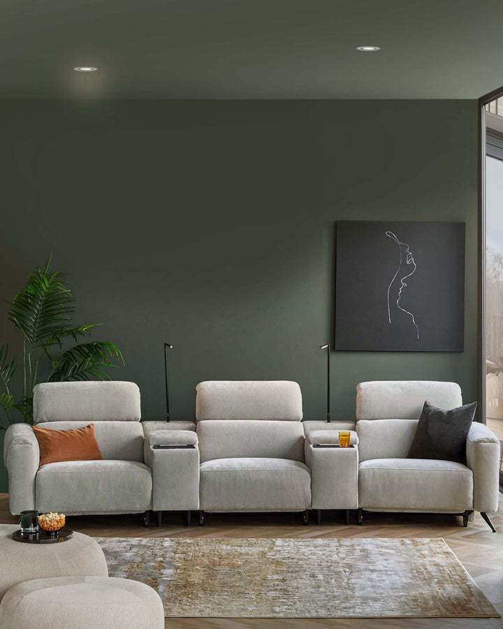 A modern, light gray sectional sofa with cup holders, accented by a dark pillow and an orange cushion, on a plush area rug.
