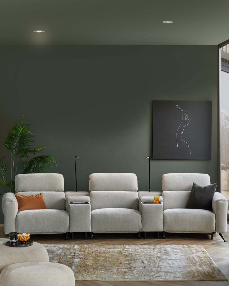 A modern, light gray sectional sofa with cup holders, accented by a dark pillow and an orange cushion, on a plush area rug.