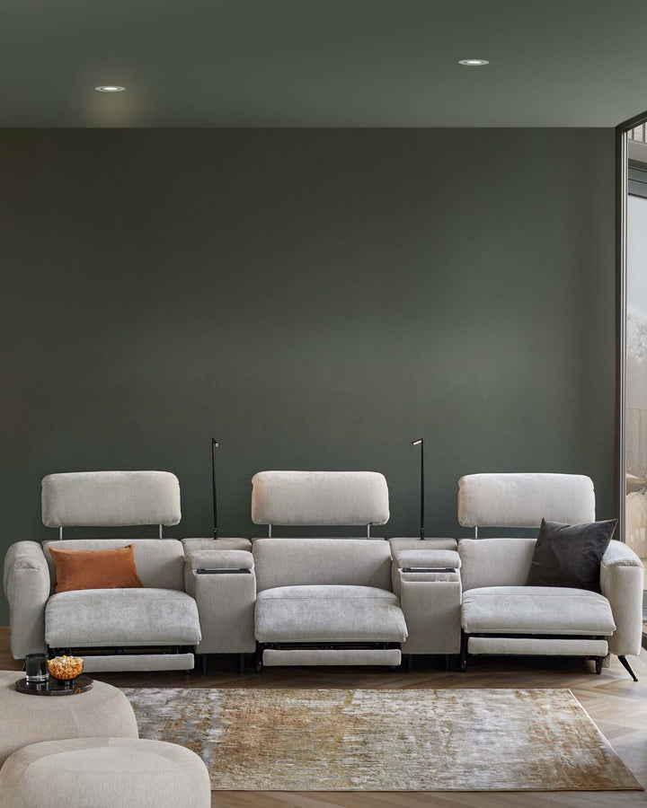 Modern grey recliner sofa with adjustable headrests, side storage, a contrasting orange cushion, and a cozy area rug.