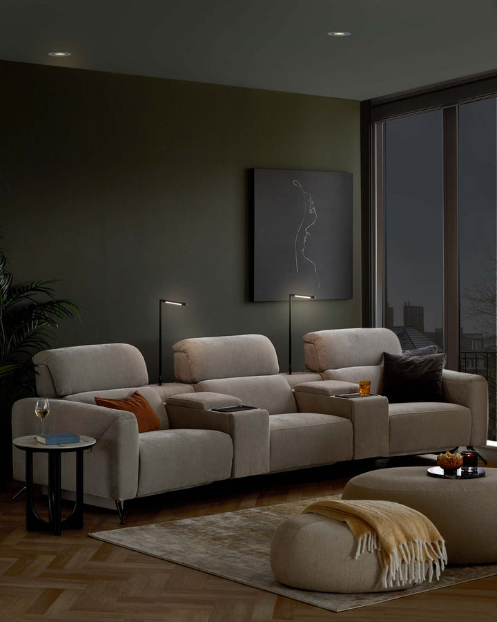 Cozy beige sectional sofa with plush cushions, side tables, and a round pouf, accented by stylish lamps and artwork.