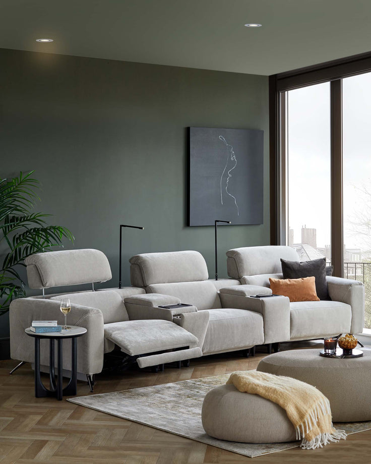 A cozy sectional sofa with recliners, a round coffee table, and a soft ottoman, accented by modern lamps and decorative pillows.