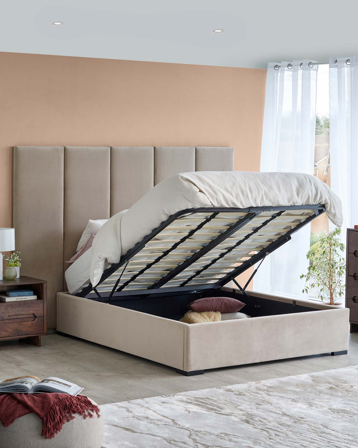 A stylish upholstered bed with a storage base, featuring a plush headboard and a cozy throw blanket beside a wooden nightstand.