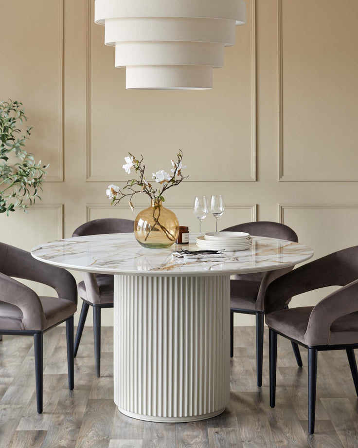 Round marble dining table with velvet chairs and a tiered pendant light. Contemporary dining room furniture.