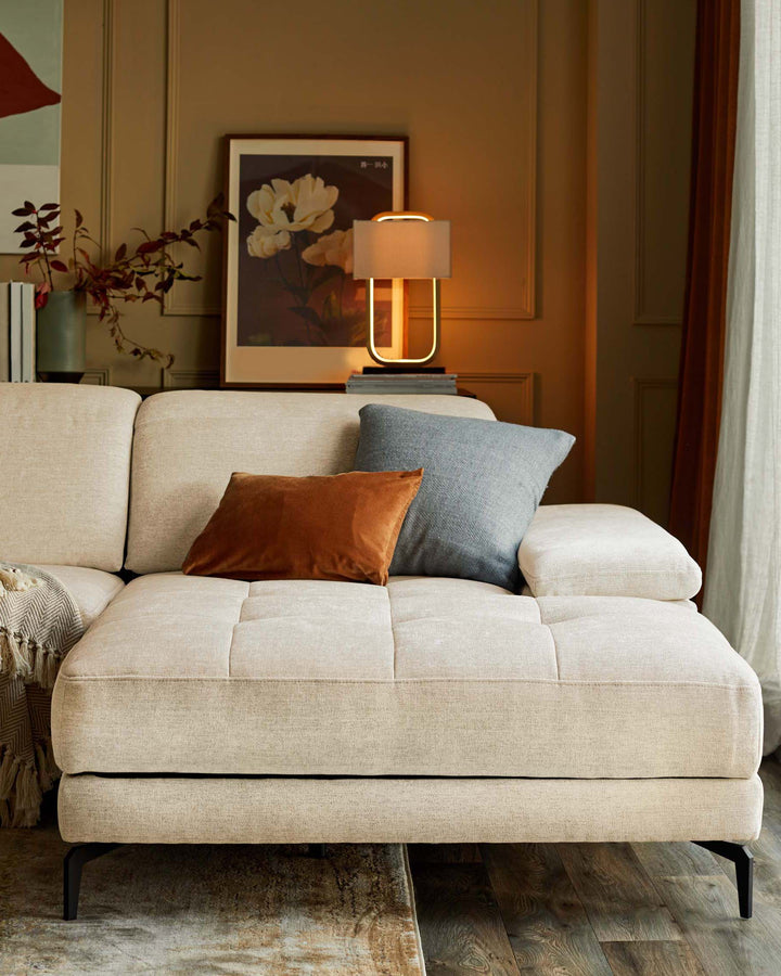 A neutral-toned sofa with a chaise end, adorned with cushions and a throw, creates a cosy and inviting living space.