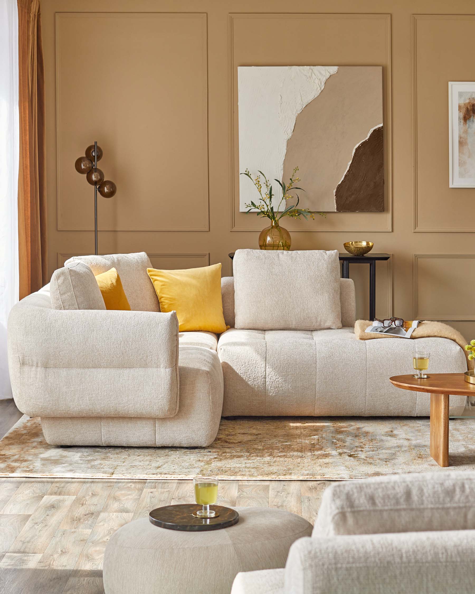 Contemporary light-colored sectional sofa with yellow accents, modern side table, accent stool, and decorative wall art.