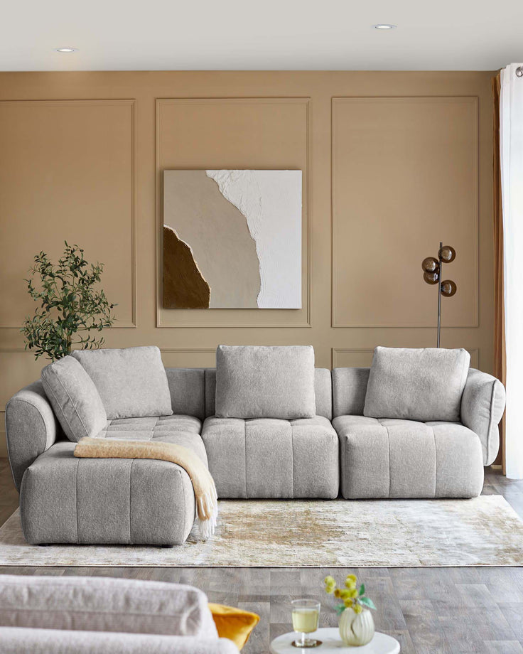 Lillian left corner chaise sofa in light grey weave fabric, displayed in a modern living room setting with neutral décor.