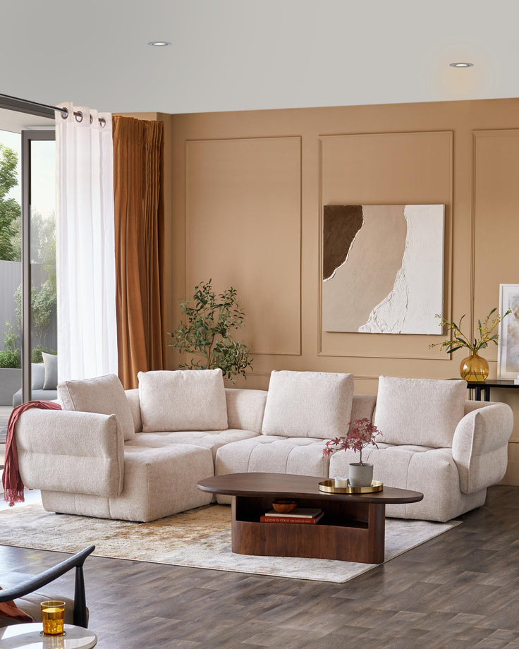Modern light beige sectional sofa with plush cushions and a curved shape, paired with a stylish oval wooden coffee table.