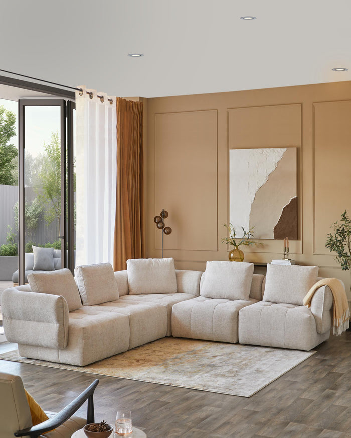 Lush, beige sectional sofa with plush cushions, complemented by a soft area rug and decorative elements in a warm, inviting space.