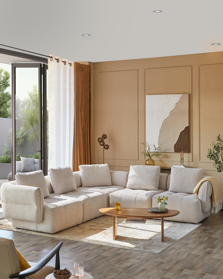 Cozy beige sectional sofa with plush cushions, a round wooden coffee table, and a simple area rug, enhanced by soft lighting.