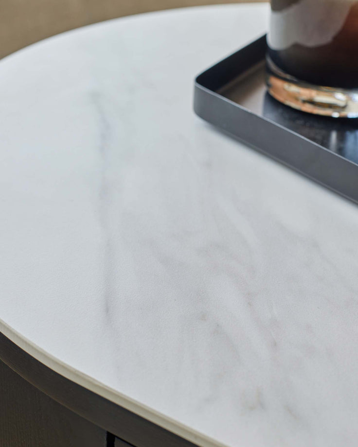Close-up of a modern side table with a white marble top and dark wood trim, showcasing a sleek design and high-quality materials.