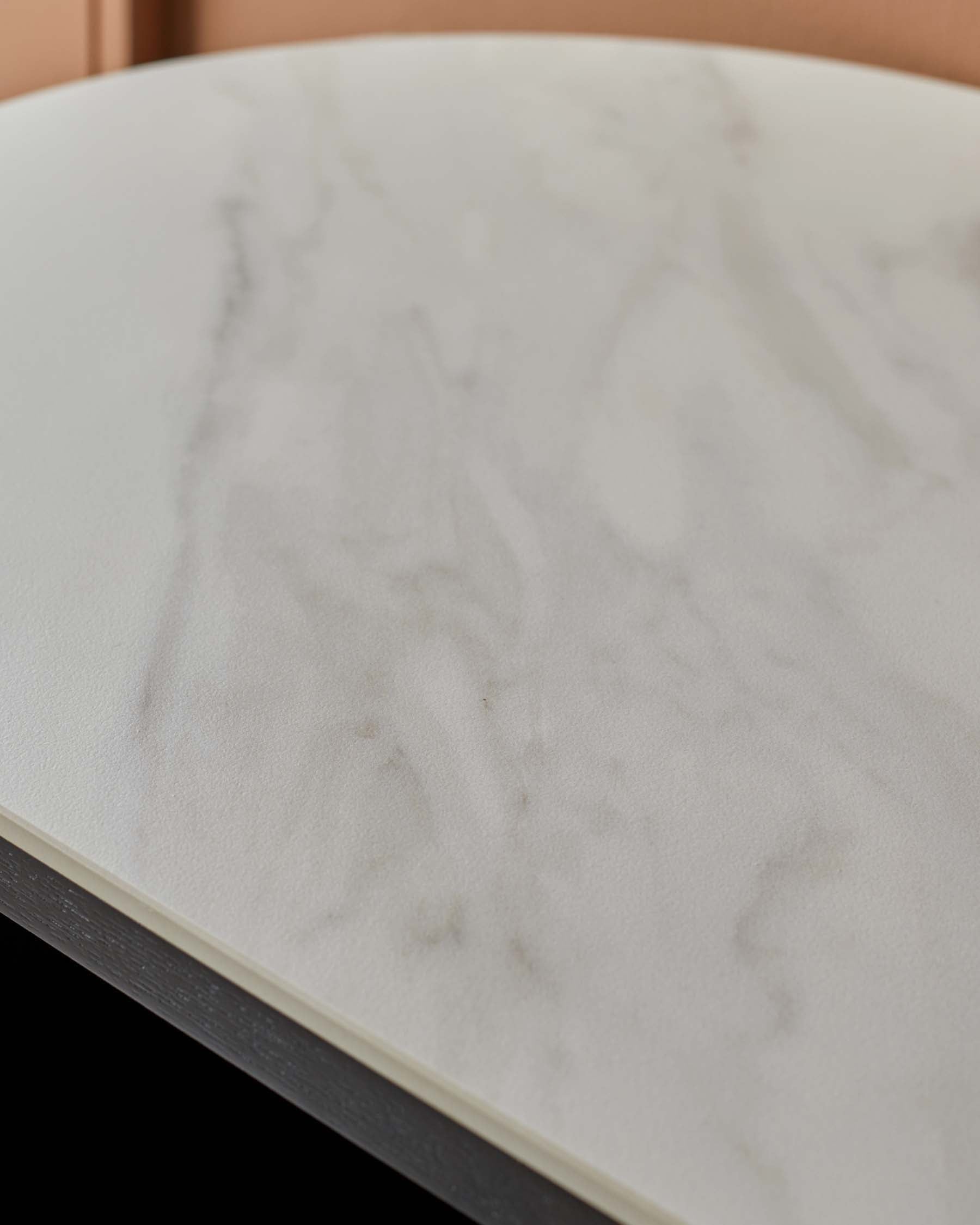 Close-up of a round marble table top with a dark wood frame. Stylish and modern furniture detail.