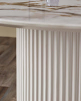 Austin 6-seater dining table with white fluted pedestal base and natural ceramic top, close-up detail view.