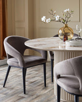 Austin 6-seater dining table in natural ceramic with round marble-effect top and fluted base, styled with gray upholstered chairs.