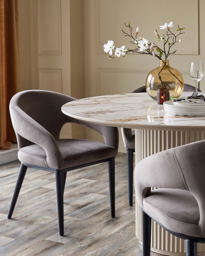 Austin 6-seater dining table in natural ceramic with round marble-effect top and fluted base, styled with gray upholstered chairs.