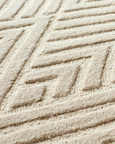 Close-up of a cream carpet with a geometric pattern. The textured surface is soft and plush, ideal for a cosy living space.