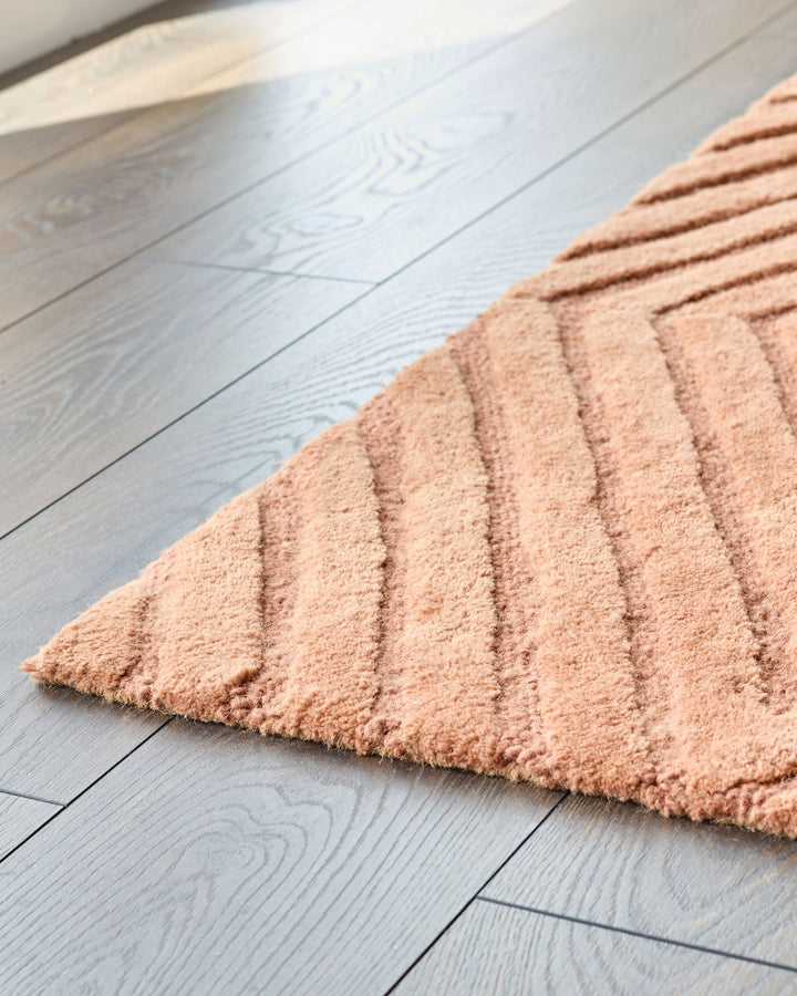 Close-up of a patterned rug on a wooden floor, showcasing texture and warmth.