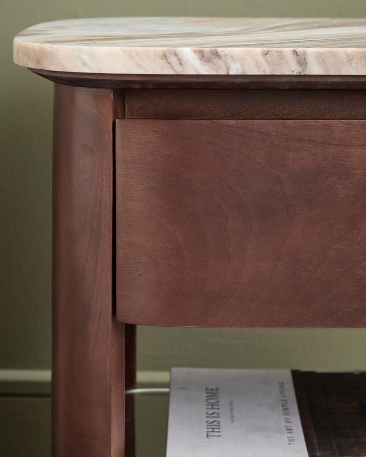 Adalynn bedside table with dark wood base and white marble top, angled side view showing drawer detail.