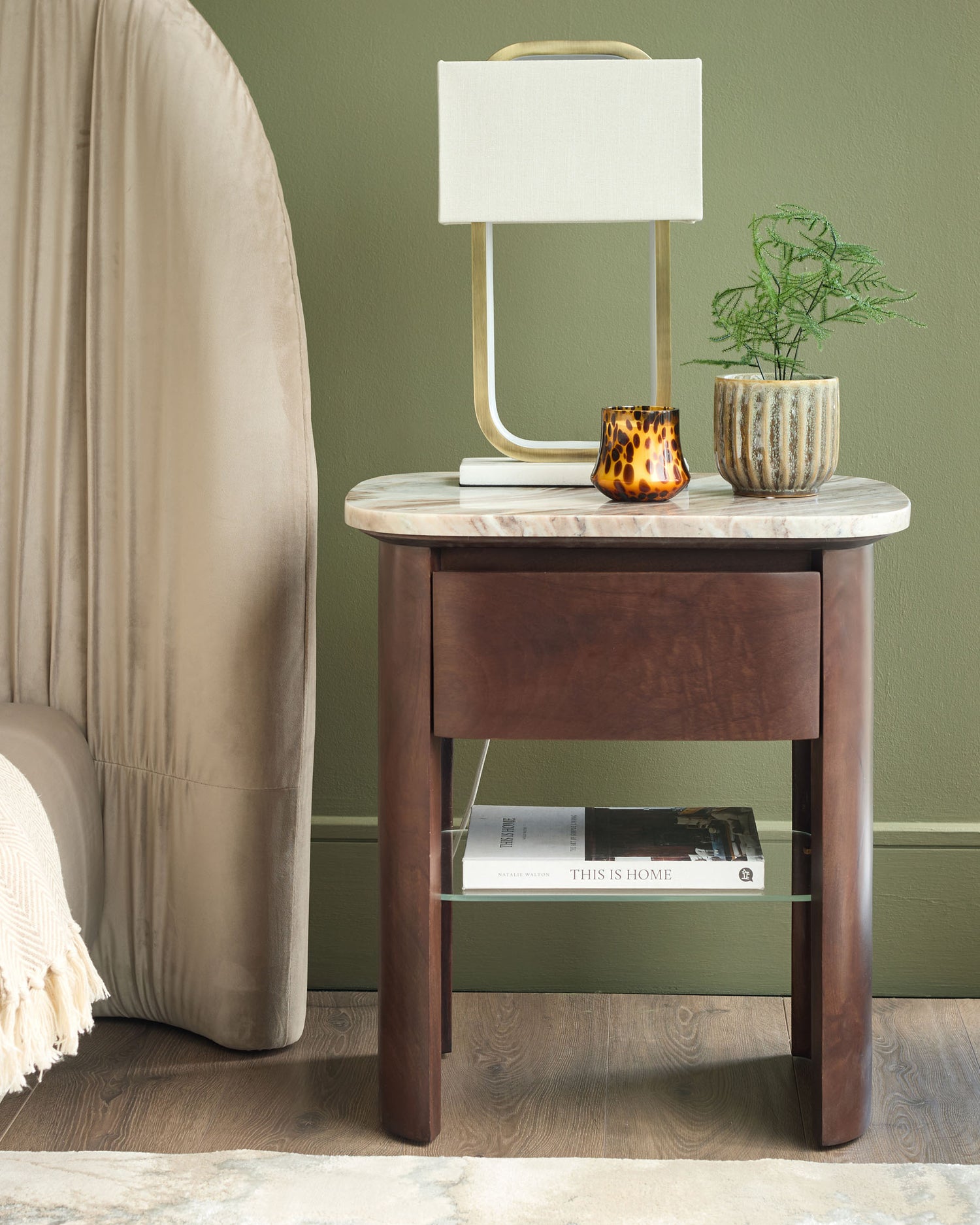Adalynn bedside table in walnut with white marble top, single drawer, lower shelf, styled in bedroom setting with lamp and décor.