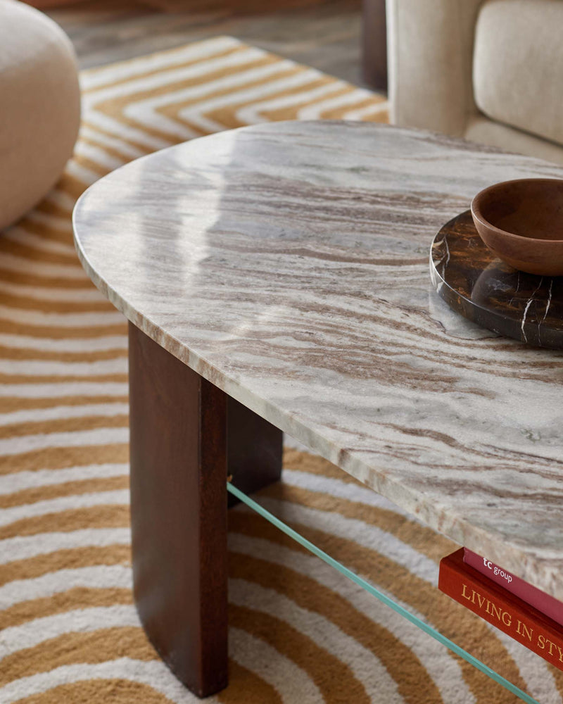 A stylish marble coffee table with a wood base sits on a patterned rug, offering a touch of understated elegance.