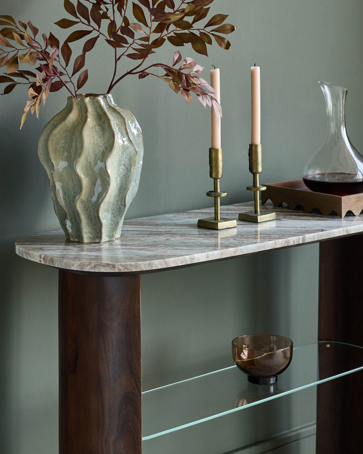 Adalynn console table in dark wood with white marble top, styled with dried florals, brass candlesticks, and decorative objects.