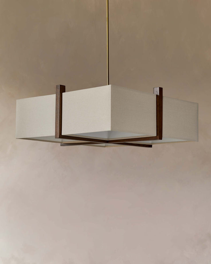 Square ceiling light fixture with pale lampshade and wood detailing hanging against a taupe wall.