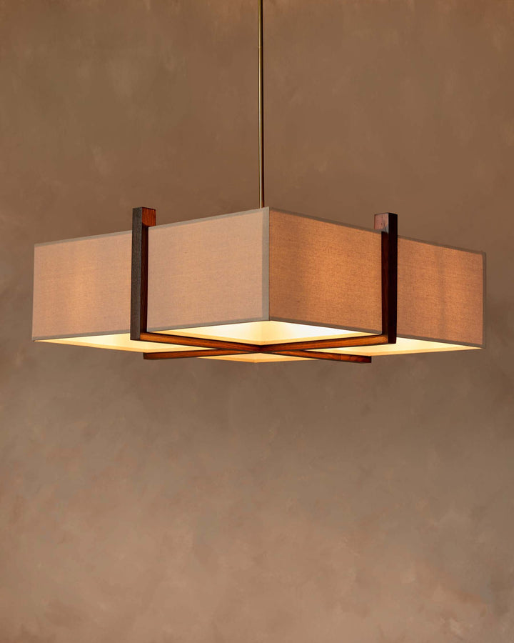 A square, beige fabric shade chandelier with a dark wood frame, hanging from a golden rod.