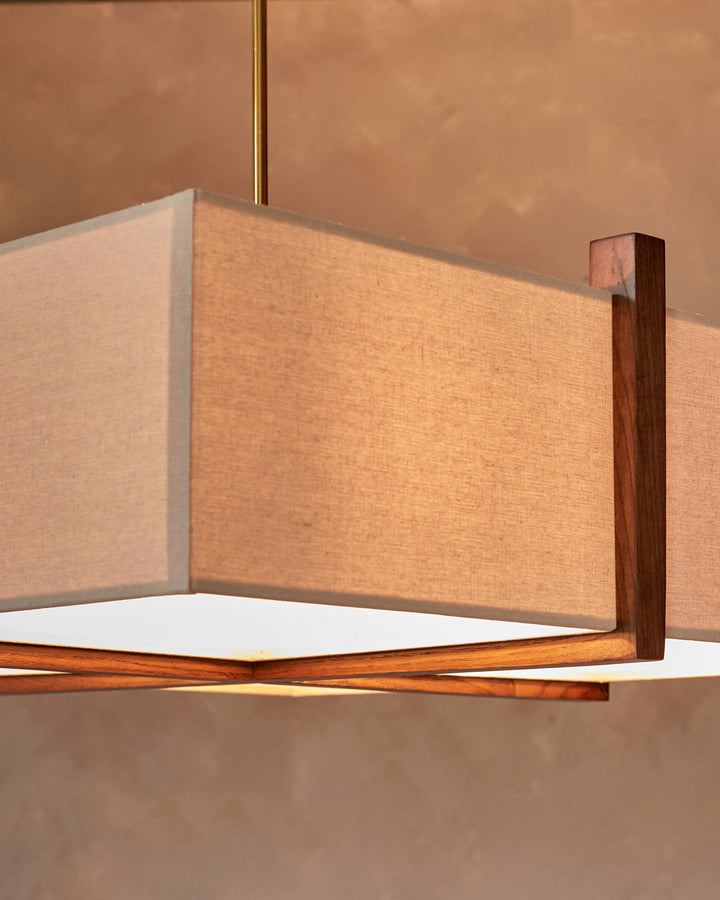 A modern boxy light fixture with a neutral fabric shade and wooden frame hangs from the ceiling.