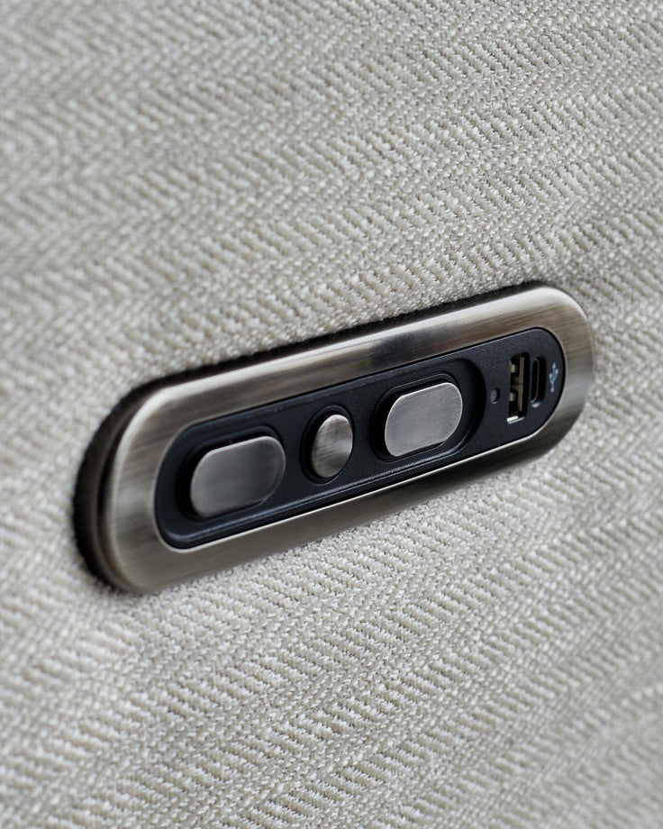 Close-up of a beige fabric sofa with bronze-coloured buttons and a USB port on the side.