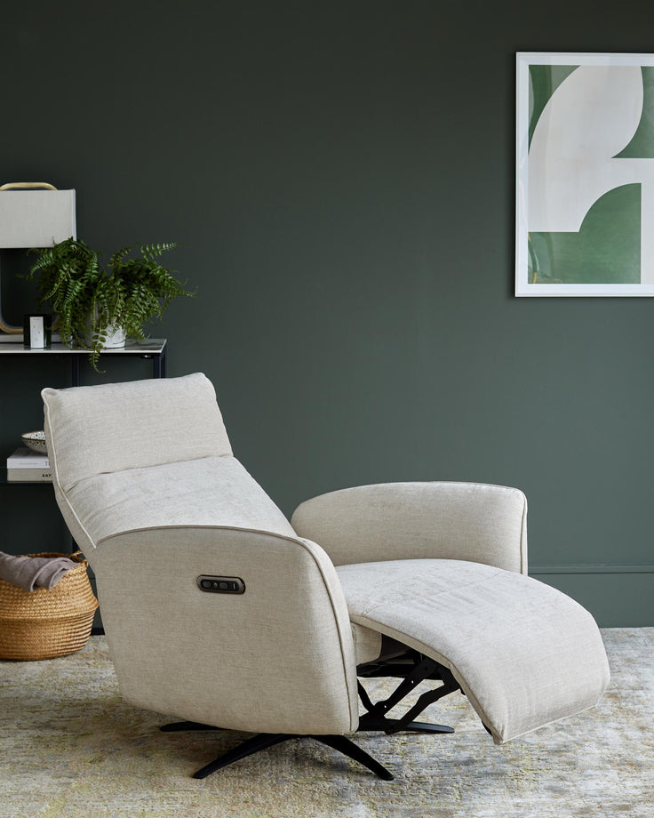 A cream recliner chair sits on a patterned rug in a living room with dark green walls and black shelving.