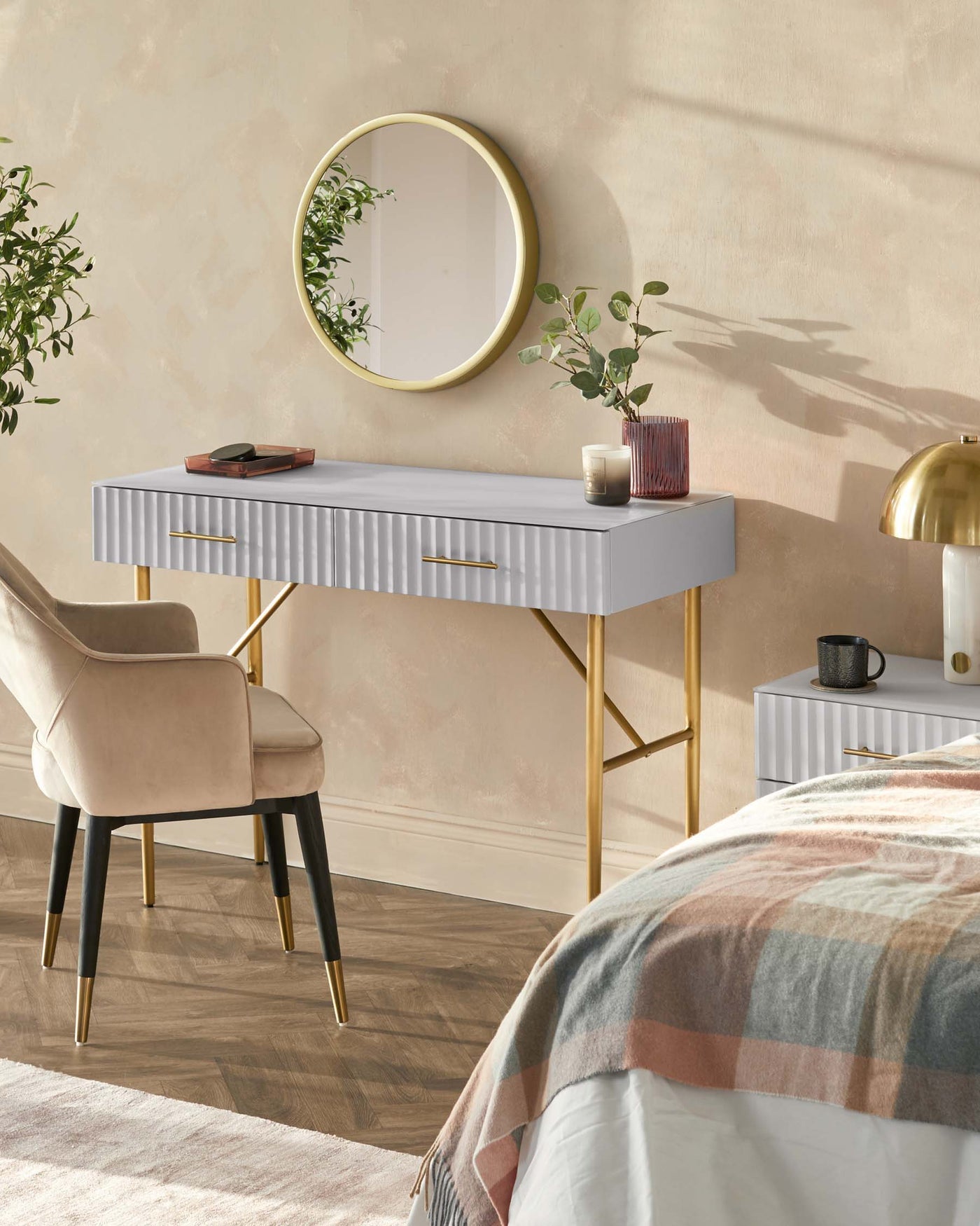 Contemporary light grey desk with a ribbed front and slim golden legs paired with a beige upholstered chair featuring black legs with golden feet accents.