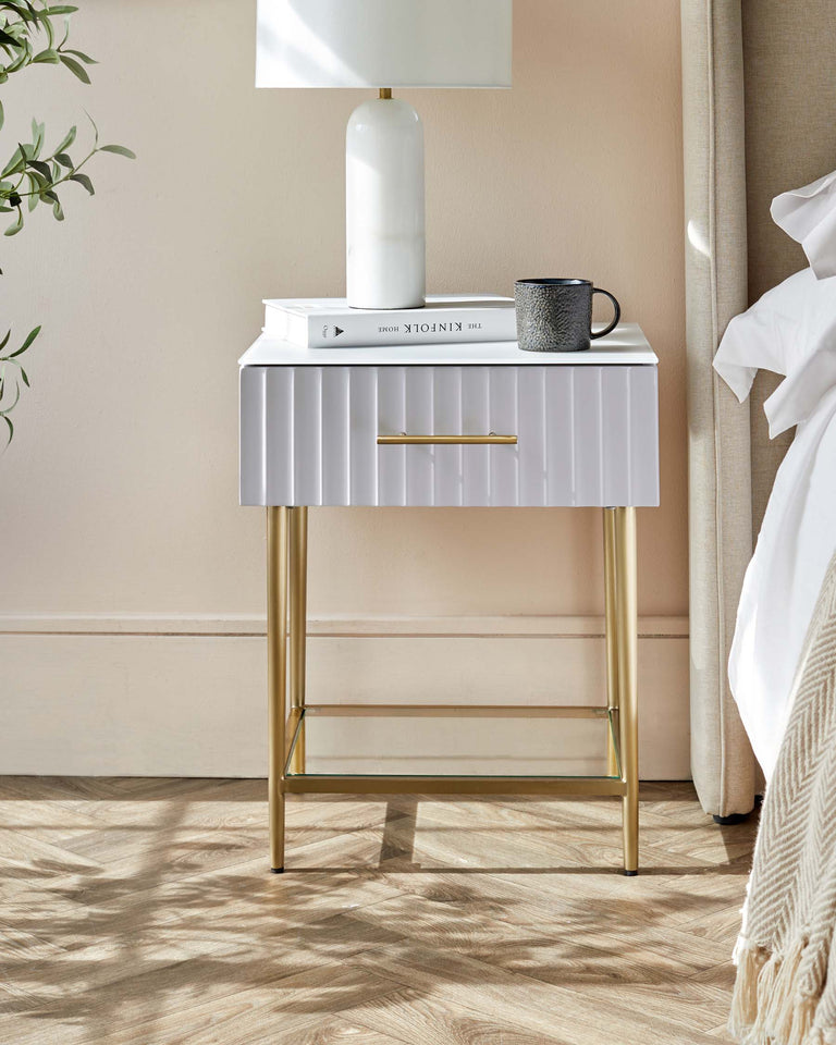 Modern white ridged nightstand with brass accents and legs, featuring a single drawer with a brass handle and a lower shelf.