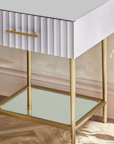 Albury bedside table with single drawer, light grey finish, brass legs and handle, glass top shelf detail.