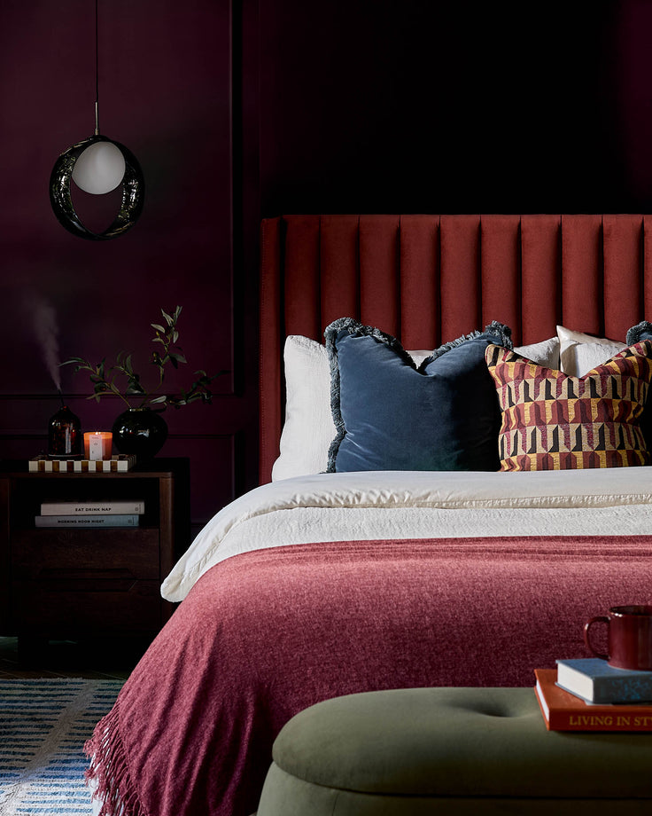Amalfi velvet king-size bed with storage in toffee red, upholstered headboard with vertical channeling, styled with pillows.