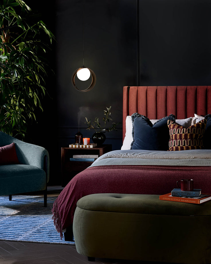 Bryce 2-drawer bedside table in dark mango wood, shown in a modern bedroom setting beside a bed.