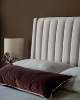 Amalfi fabric double bed with ivory upholstered headboard featuring vertical channel quilting, styled with burgundy and cream pillows.