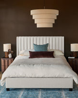 Ivory fabric double bed with vertical channel headboard, displayed in a styled bedroom setting with bedding and pillows.
