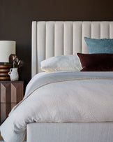 Amalfi fabric double bed in ivory with vertical channel headboard, styled with bedding and decorative pillows.