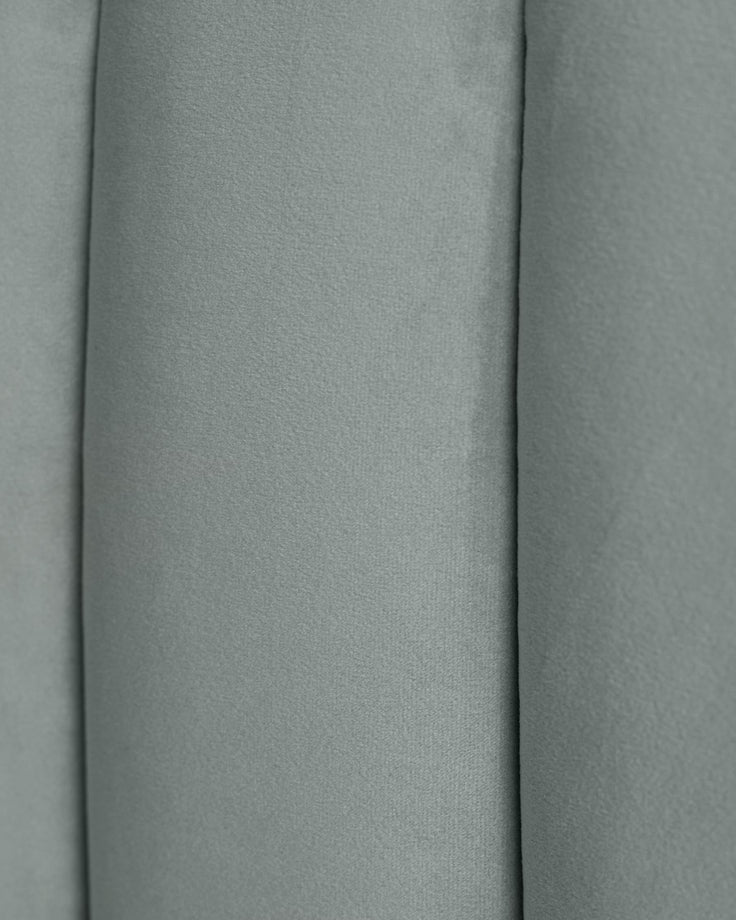Close-up of a grey plush, upholstered furniture panel with vertical pleats. Soft texture and elegant design.