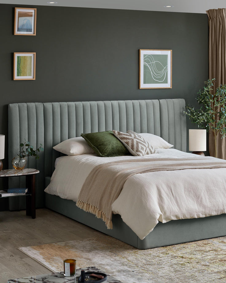 Bedroom features bed with green headboard, side table, patterned rug and framed wall art.