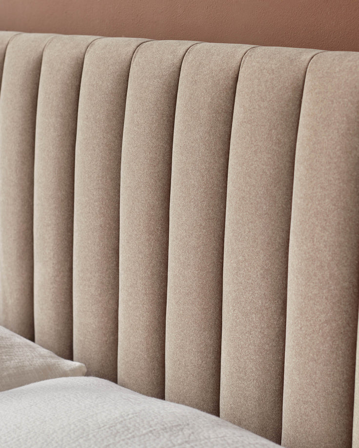 Close-up of a stylish beige headboard with a channel-tufted design. Cosy and inviting bedroom furniture.