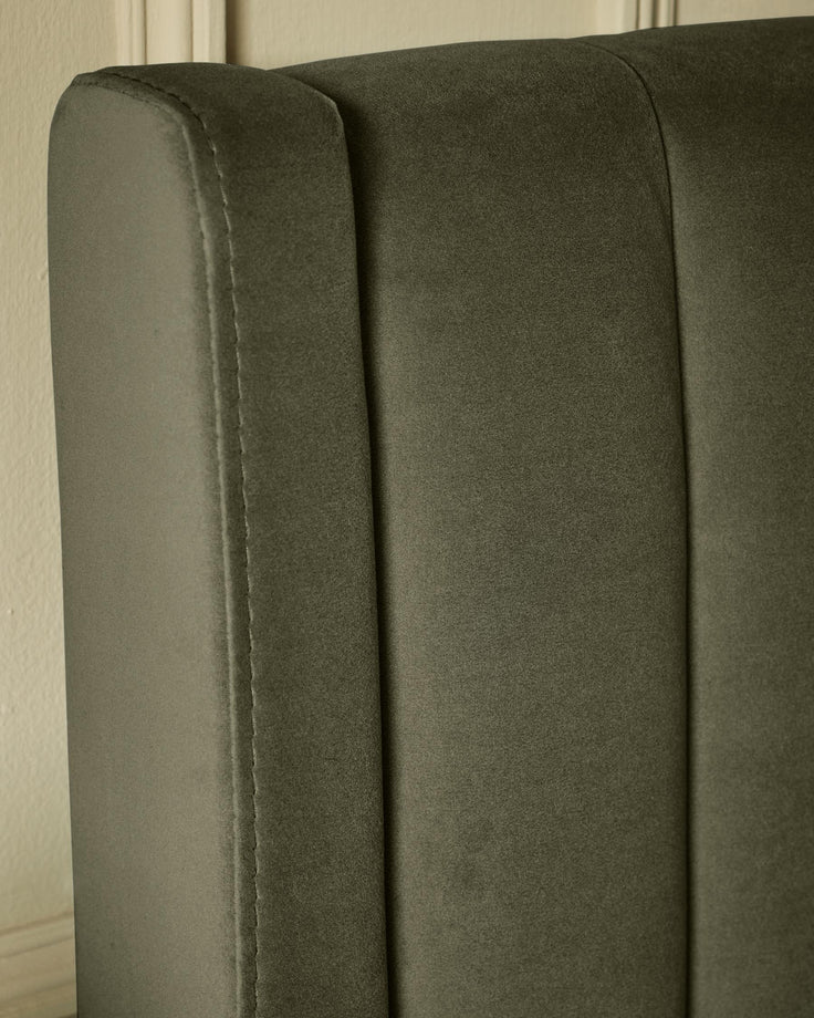 Close-up of a grey upholstered headboard featuring vertical panels and detailed stitching, adding a touch of elegance to any bedroom.