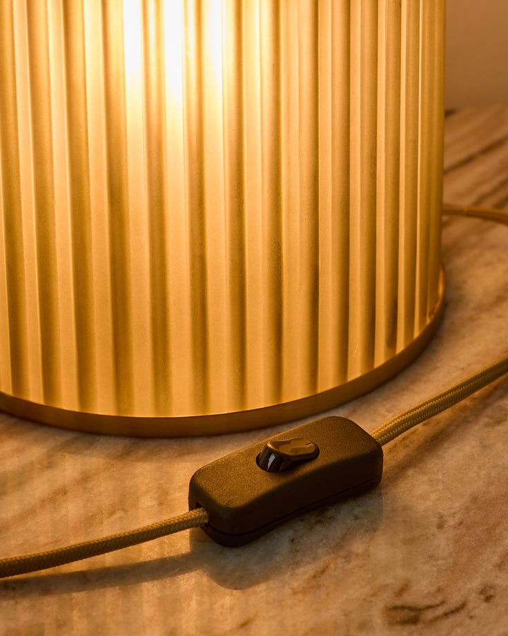 Amalfi table lamp with pleated golden shade and inline switch on fabric cord, close-up detail view.