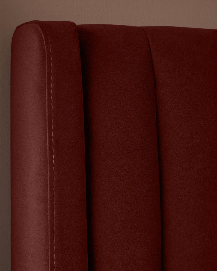 A close-up of a plush, claret-coloured headboard with a vertical channel design. Perfect for a sophisticated bedroom.
