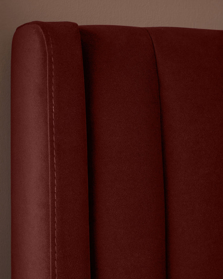 A close-up of a plush, claret-coloured headboard with a vertical channel design. Perfect for a sophisticated bedroom.